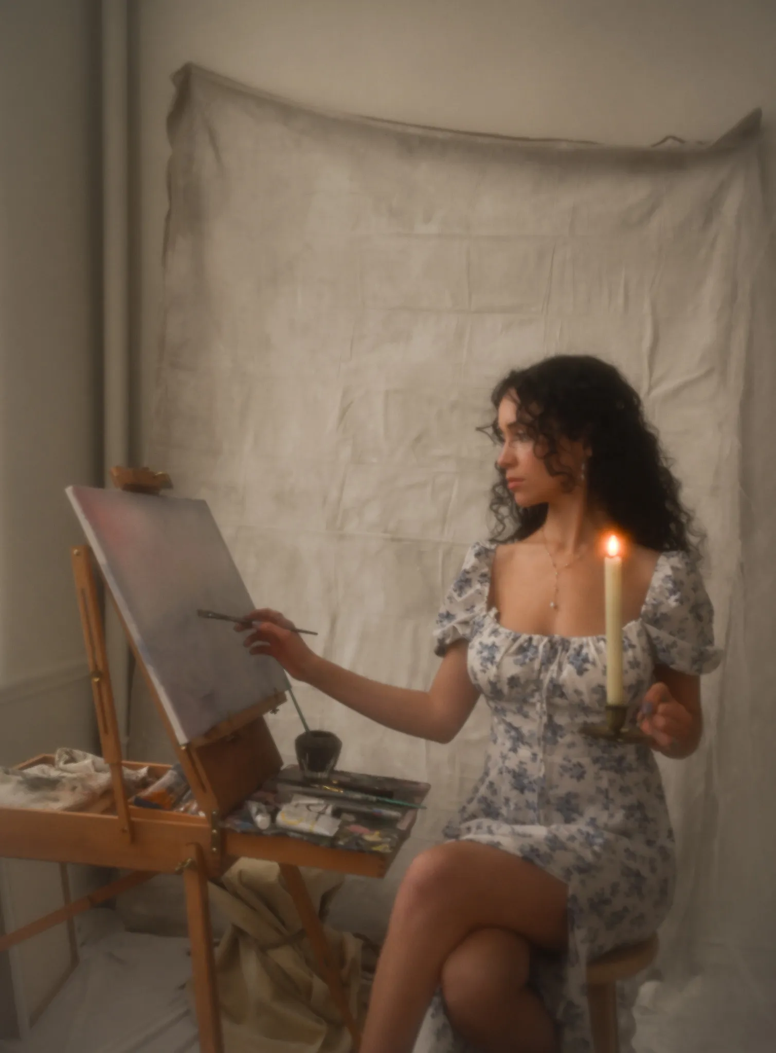 Abigail painting at her easel by candlelight
